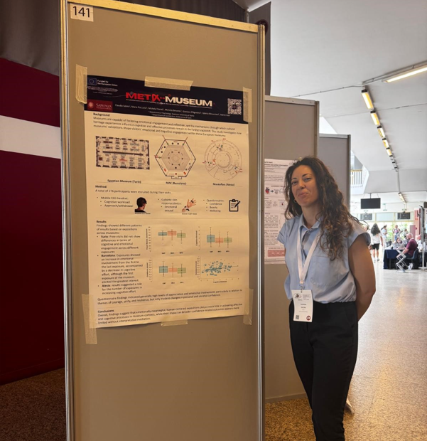 a woman standing in front of a poster presentation at a conference hall.